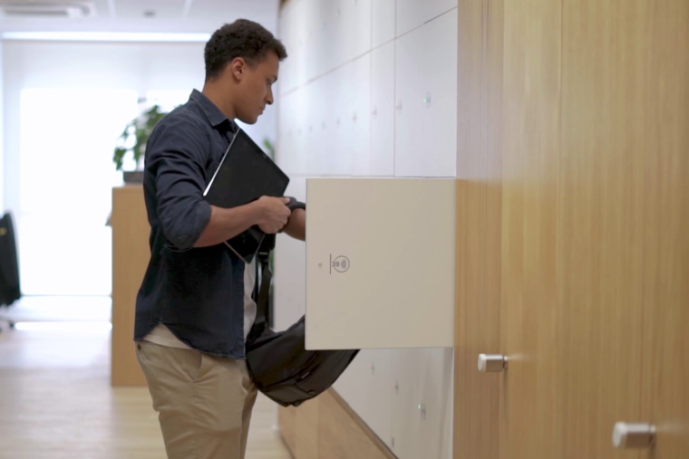 Ein junger Mann ist gerade dabei, seinen Rucksack in einem praktischen Schließfach zu verstauen.